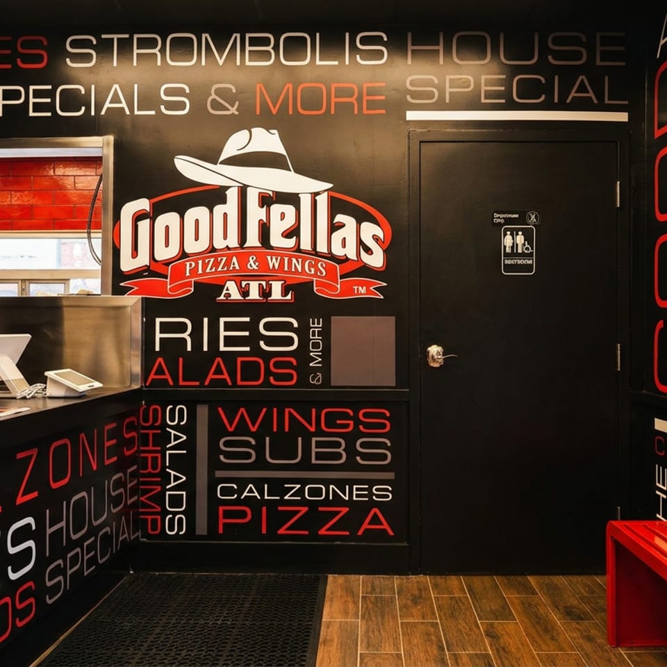 Goodfellas Pizza & Wings interior with black walls, red and white text, and a red bench.